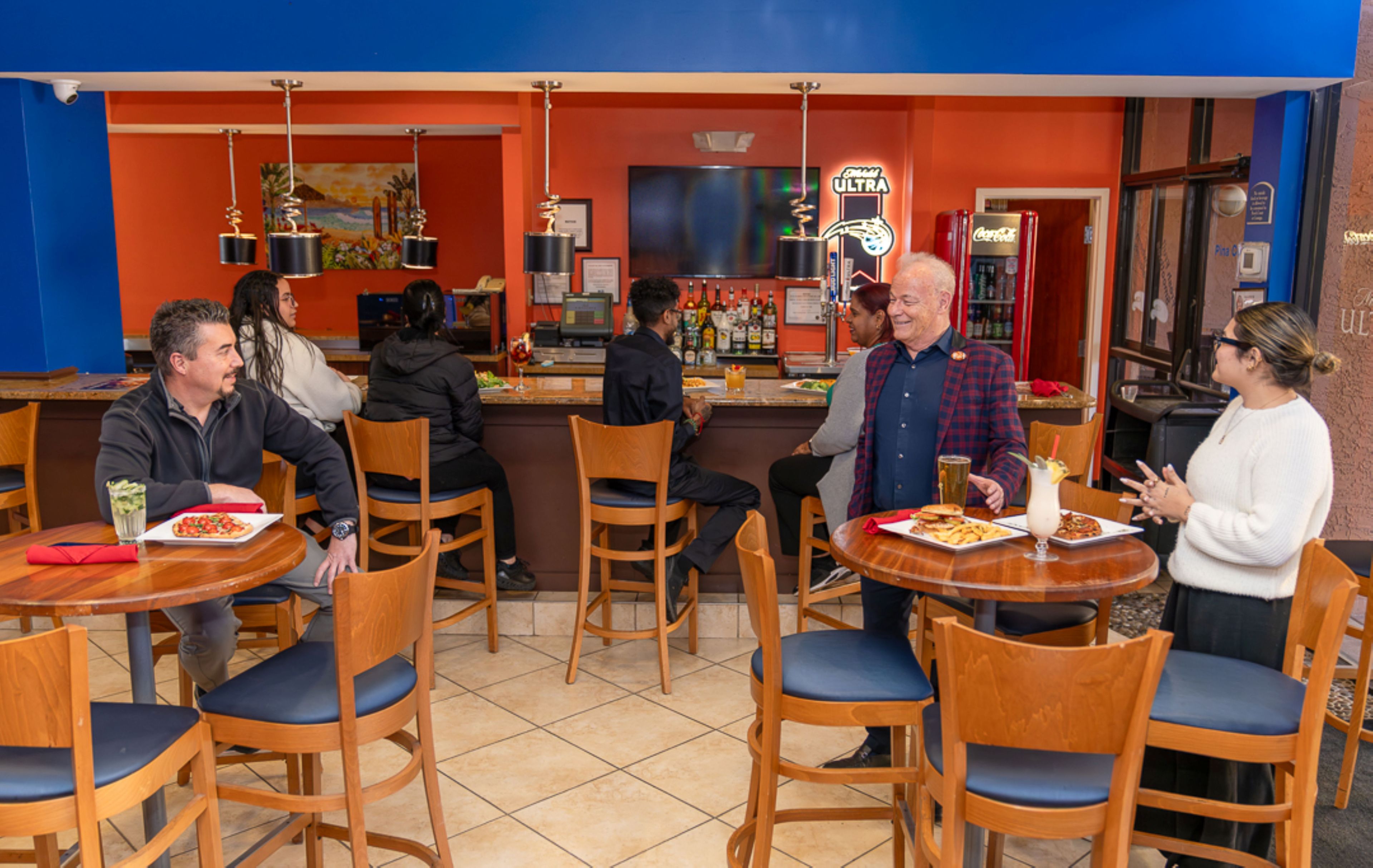A restaurant interior with wooden chairs, tables, and a bar area.