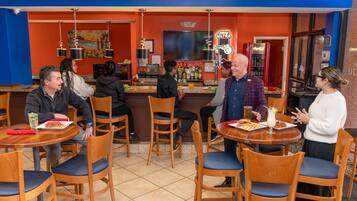 A restaurant interior with wooden chairs, tables, and a bar area.