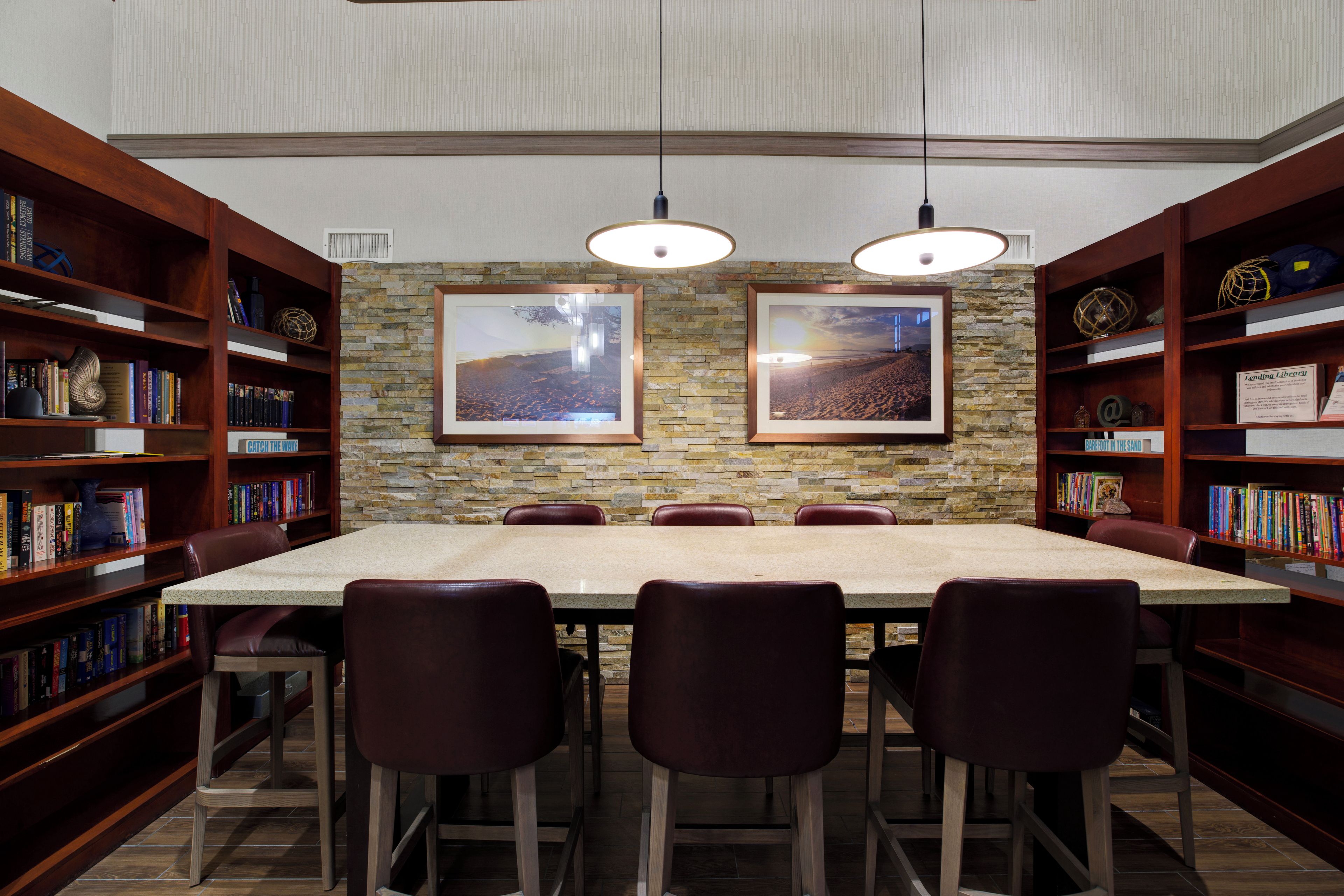 A library with a long table and chairs, surrounded by bookshelves.
