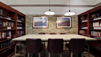 A library with a long table and chairs, surrounded by bookshelves.