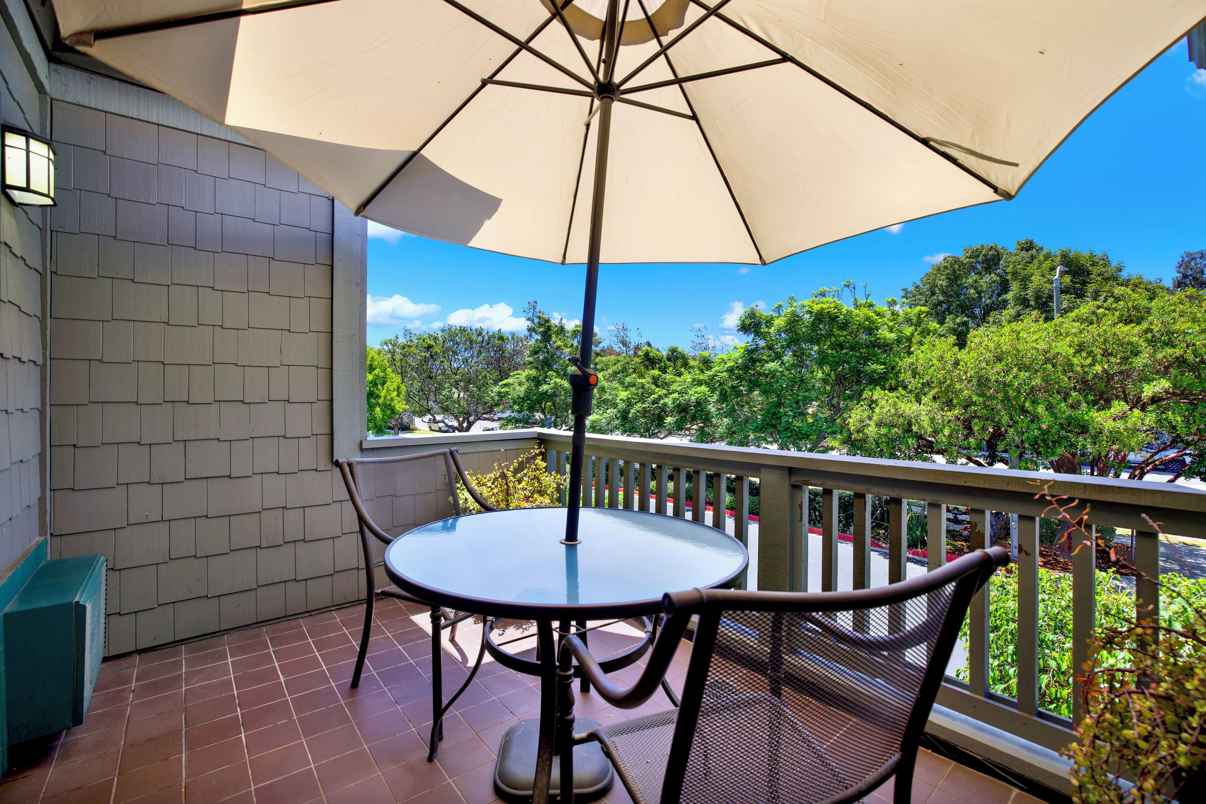 Un patio techado con una mesa y sillas, con vistas a un paisaje verde exuberante.