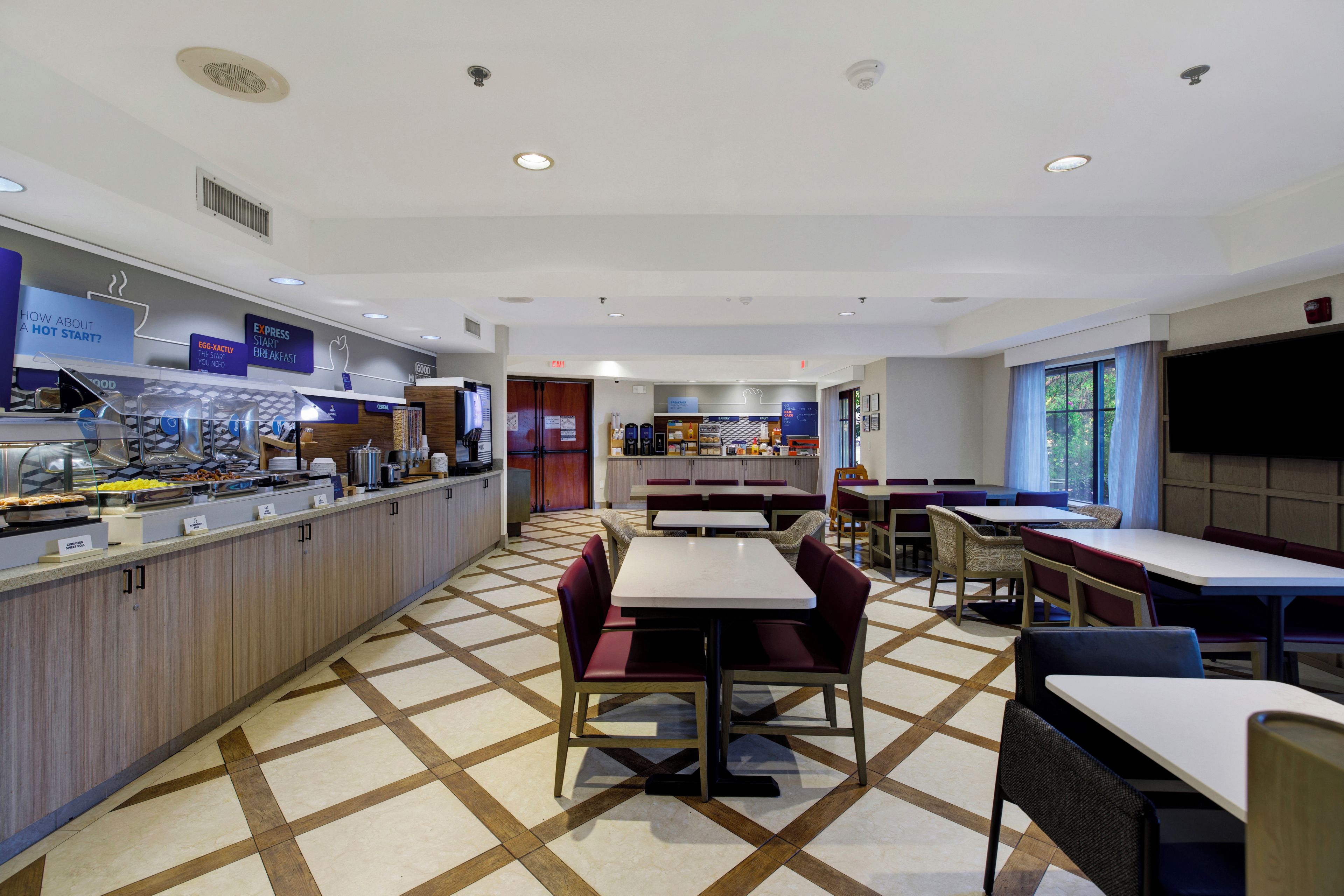 A breakfast area with a buffet, seating, and a view of the outdoors.