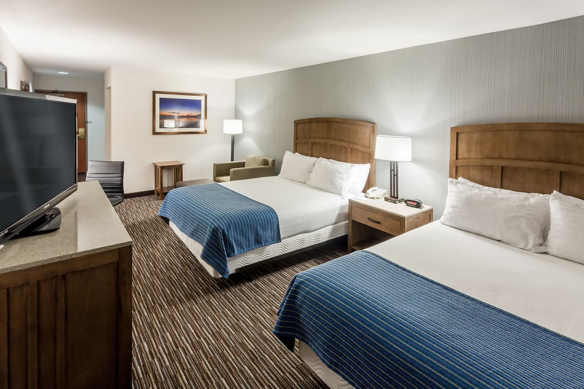 A hotel room with two beds, a TV, a desk, and a small table.