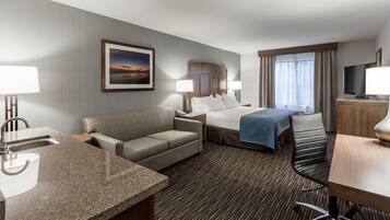 A hotel room with a bed, a sofa, a desk, a TV, and a window with curtains.