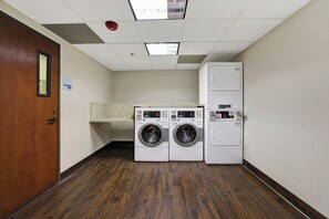A laundry room with two front-loading washing machines and a stacked dryer. - Holiday Inn Express & Suites Carpinteria by IHG (Carpinteria)