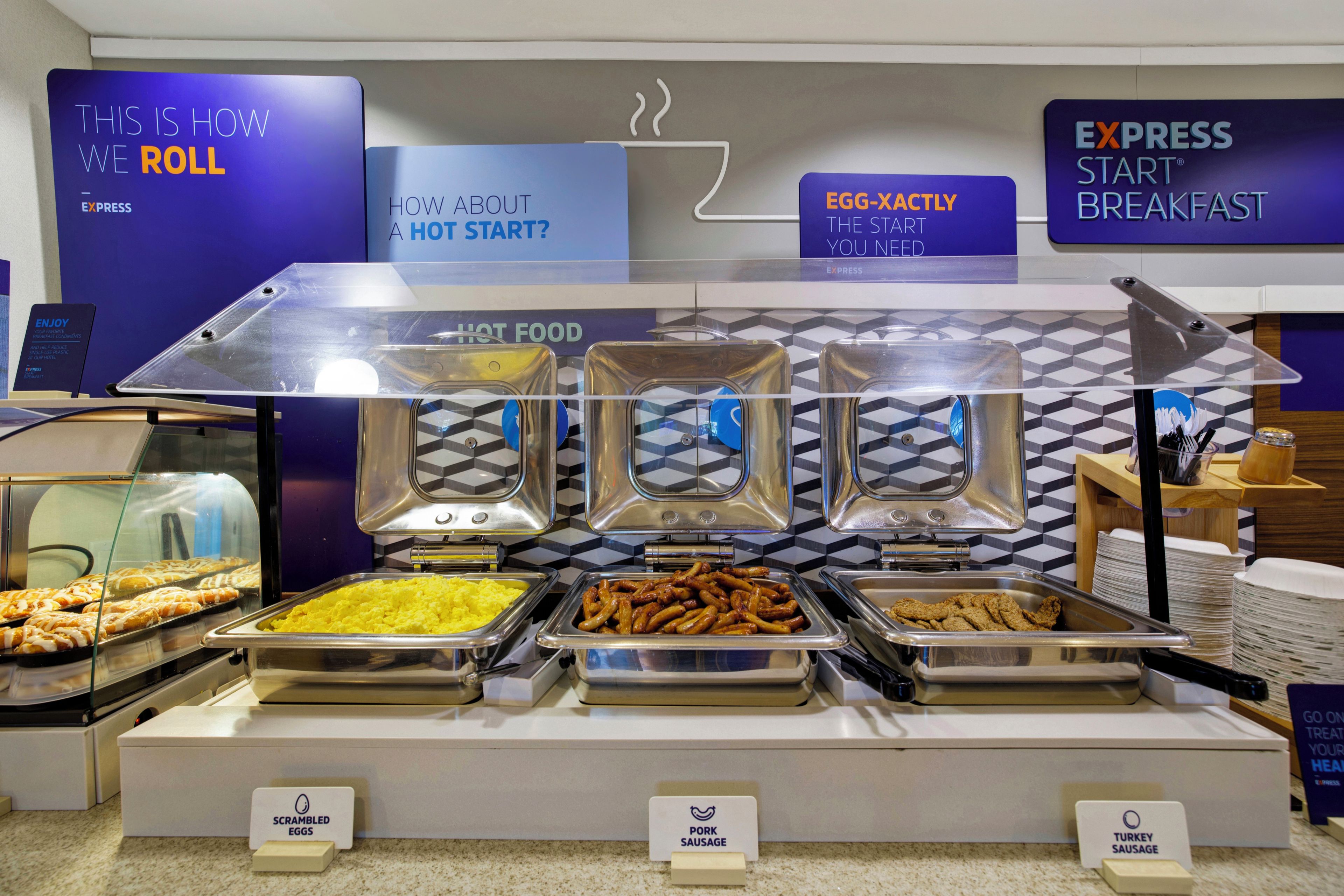 A buffet setup with labeled food sections including scrambled eggs, pork sausage, and turkey sausage.