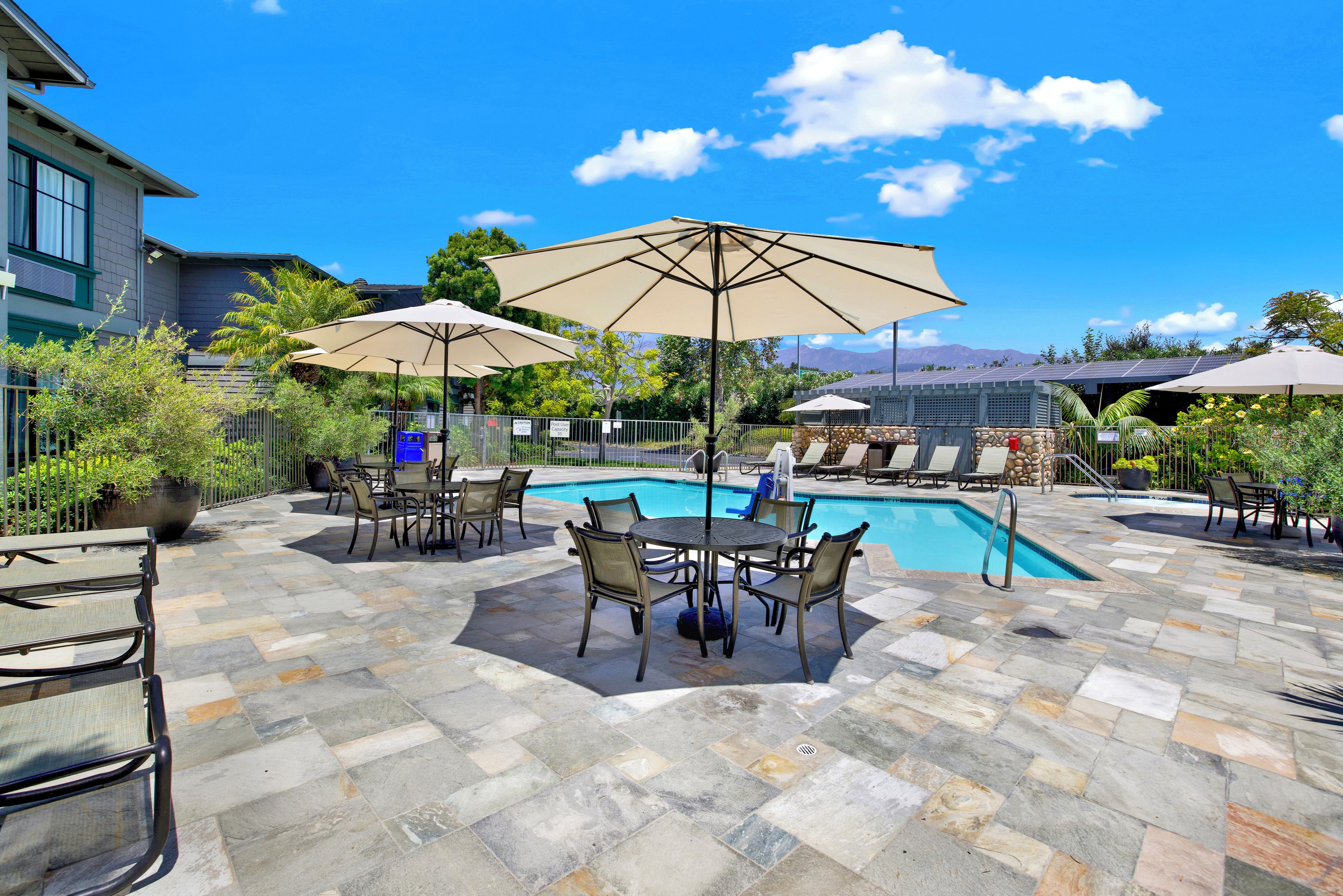 A poolside area with lounge chairs, umbrellas, and a pool.