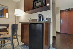 A compact kitchenette with a refrigerator, microwave, and coffee maker.