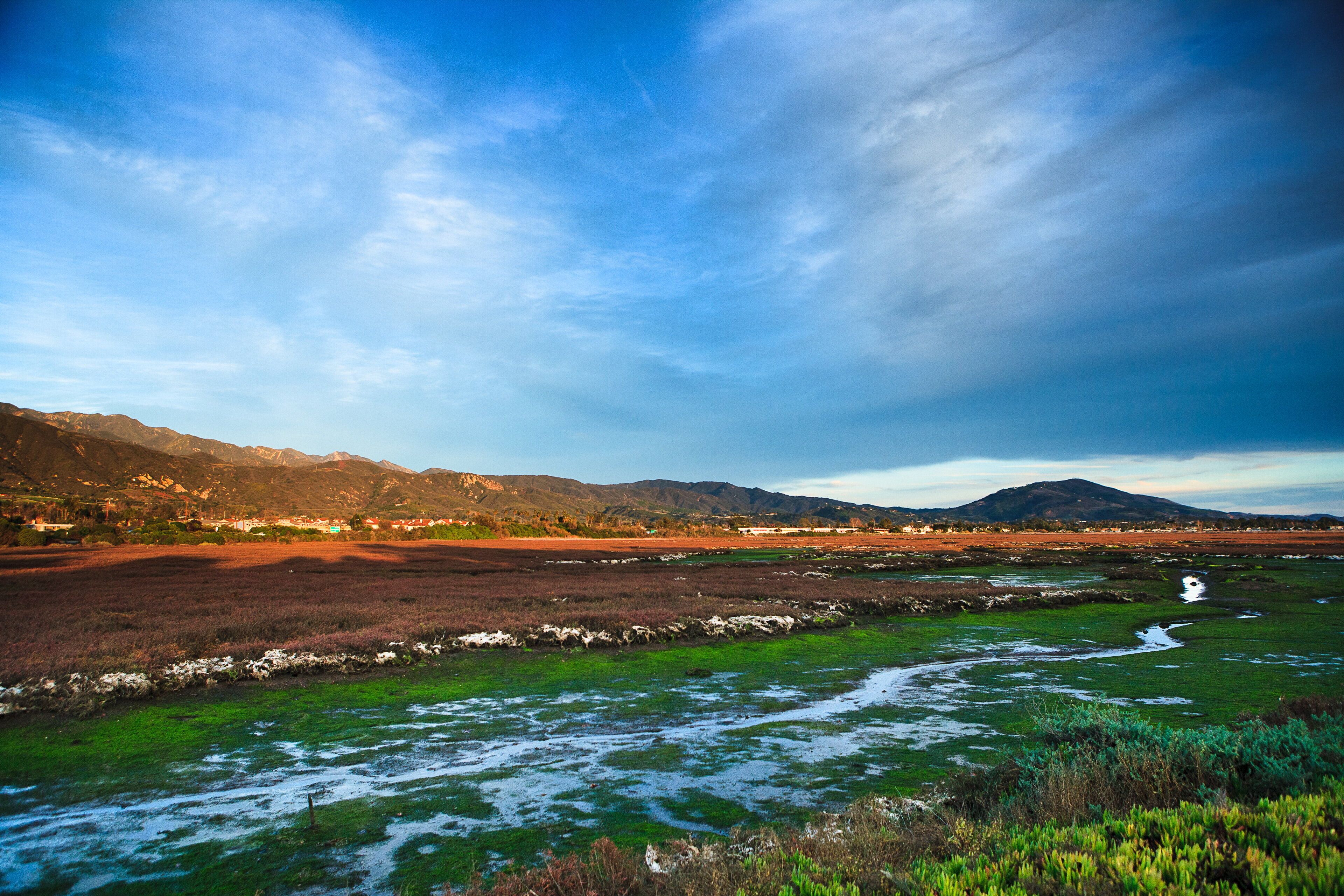 A landscape with a river, mountains, and a clear sky.