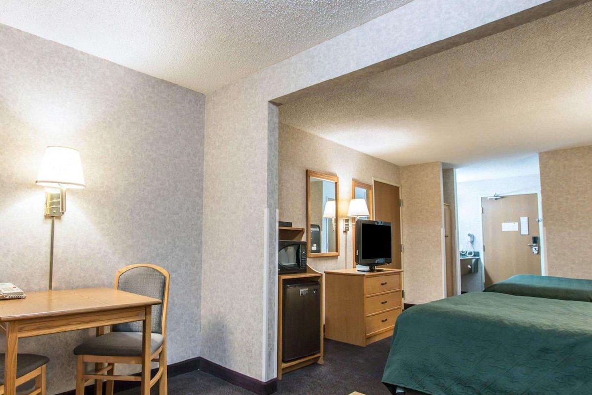 Une chambre d’hôtel équipée d’un lit, d’un bureau avec une chaise, d’une télévision, d’un four à micro-ondes et d’un réfrigérateur.