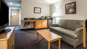 A compact living space with a kitchenette, a sofa, a TV, and a lamp. - Quality Suites San Diego Otay Mesa (San Diego)