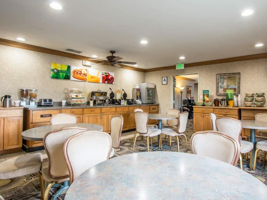 A hotel room with a kitchenette, dining area, and a ceiling fan.