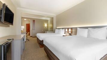 A hotel room with two beds, a desk, a television, and a bathroom visible through an open door.