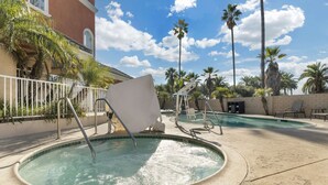 A pool area with a circular hot tub, lounge chairs, and palm trees. - Comfort Suites Oceanside Camp Pendleton Area (Oceanside)