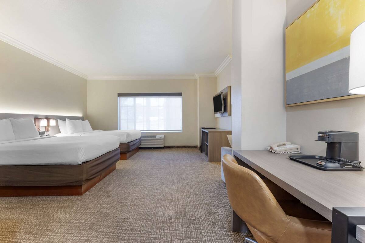 A hotel room with a bed, a desk, a chair, a TV, and a window.