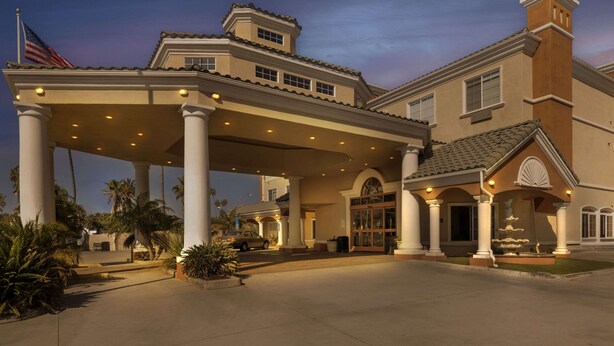 A hotel with a covered entrance, palm trees, and an American flag. - Comfort Suites Oceanside Camp Pendleton Area (Oceanside)
