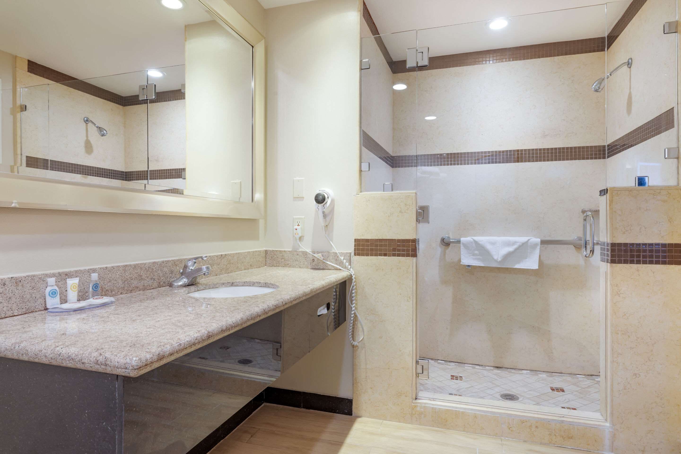 A bathroom with two sinks, a mirror, a shower, and a towel rack.