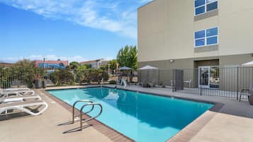 Una piscina al aire libre, sillones reclinables de piscina
