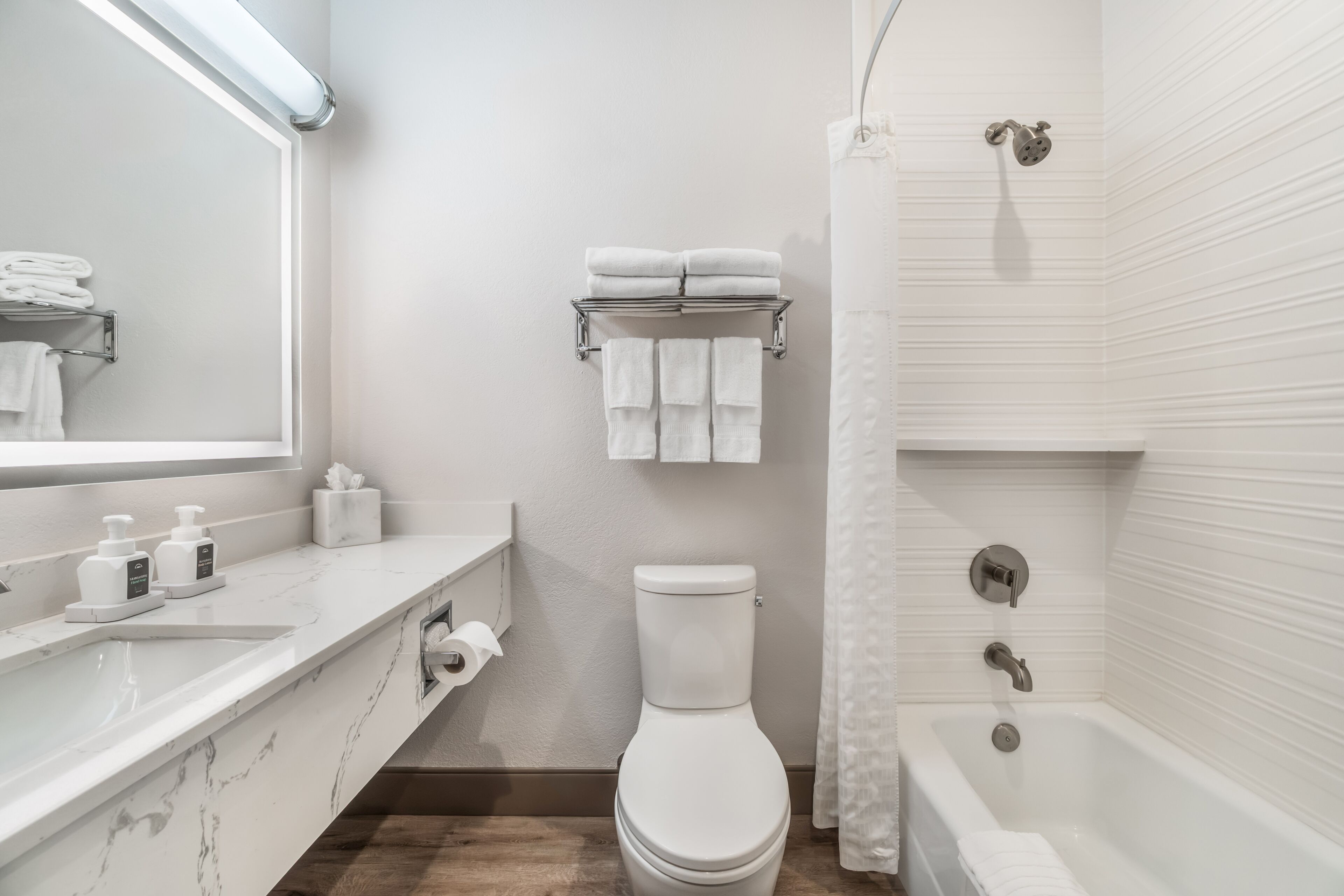 Un baño moderno con lavamanos de mármol, inodoro, bañera y cortina de ducha.