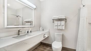 A modern bathroom with a marble countertop, a toilet, a towel rack, and a shower curtain.