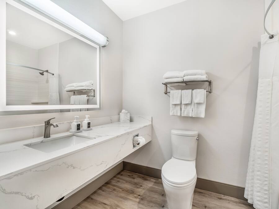 A modern bathroom with a marble countertop, a toilet, a towel rack, and a shower curtain.