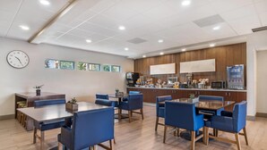 A modern dining area with a bar, seating, and a clock on the wall. - The Hanford Hotel, an Ascend Collection Hotel (Hanford)