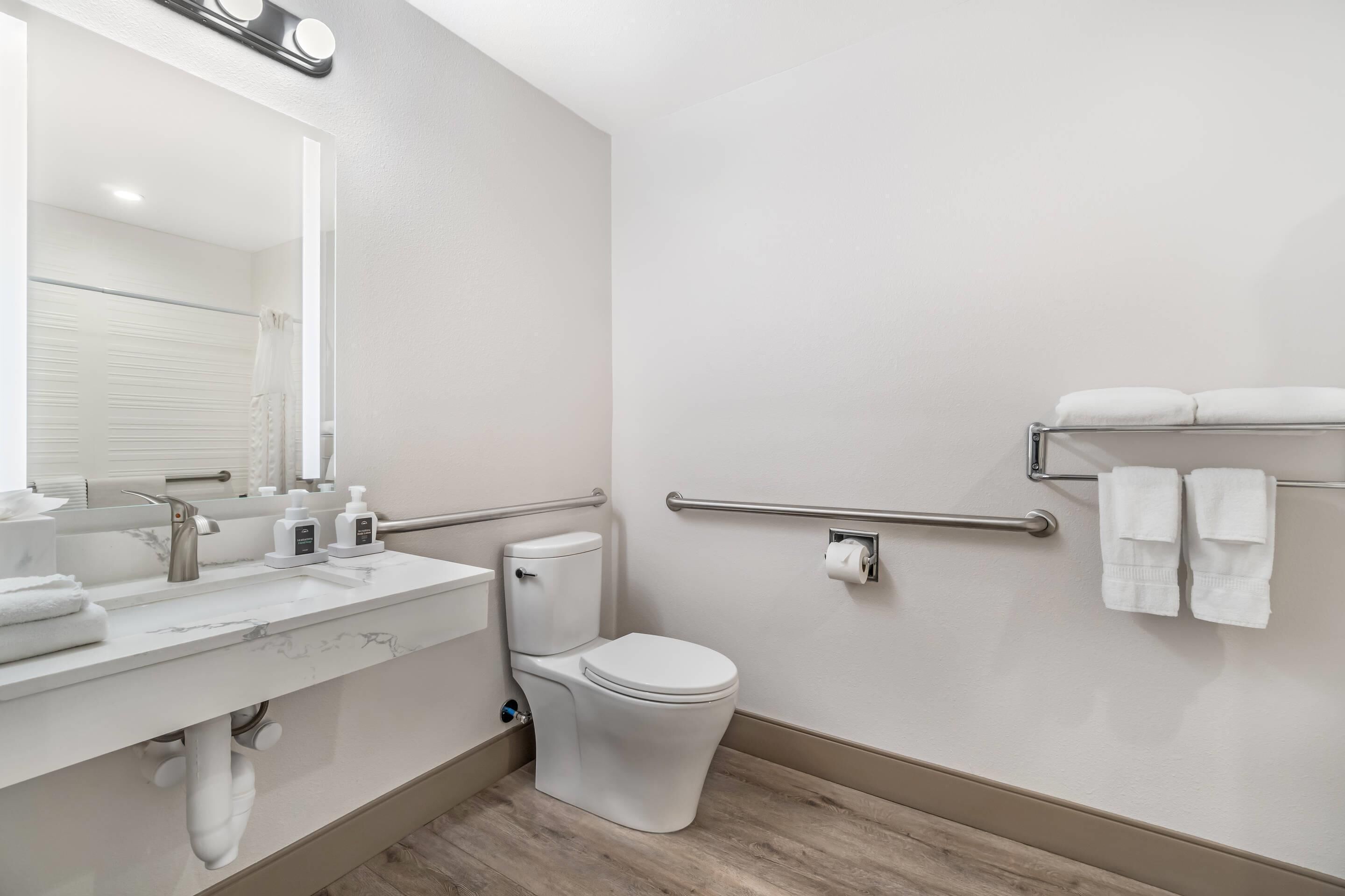 Un baño moderno con inodoro, lavamanos y dispensadores de gel antibacterial.