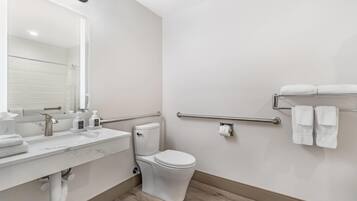 Un baño moderno con inodoro, lavamanos y dispensadores de gel antibacterial.