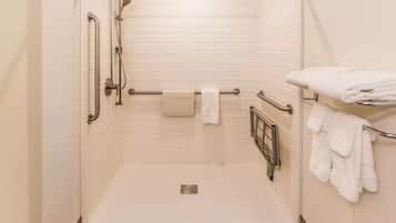 Un baño moderno con ducha a nivel, barras de apoyo, perchero y piso de madera.