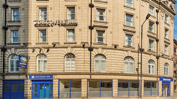 Un edificio de varios pisos con un llamativo letrero de 'Discovery Inn' a nivel de calle.