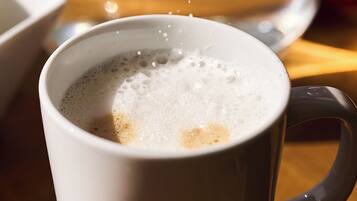 A white cup with a handle, filled with a beverage, and steam rising from it.