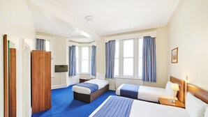 Habitación de hotel con dos camas, un armario de madera, un televisor y ventanas grandes con cortinas.