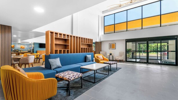 Un vestíbulo moderno con un sofá azul, sillones amarillos y una estantería de madera.