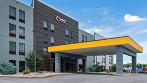 Un hotel moderno con fachada gris, un toldo amarillo y un cartel que dice "Comfort Inn & Suites".
