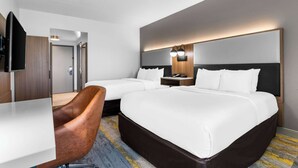 Una habitación de hotel con dos camas, un escritorio, una silla y un televisor.