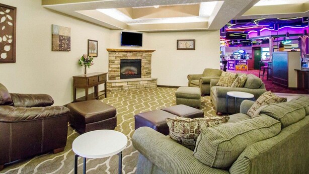 A spacious living room with a stone fireplace, comfortable seating, a flat-screen TV, and a bar area with neon lights.
