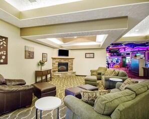 A spacious living room with a stone fireplace, comfortable seating, a flat-screen TV, and a bar area with neon lights. - Comfort Inn & Suites Deadwood (Deadwood)