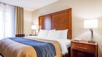 A hotel room with a large bed, two bedside tables, a lamp, and a telephone.