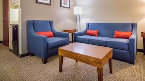 A hotel room with two blue sofas, a wooden coffee table, and a lamp.