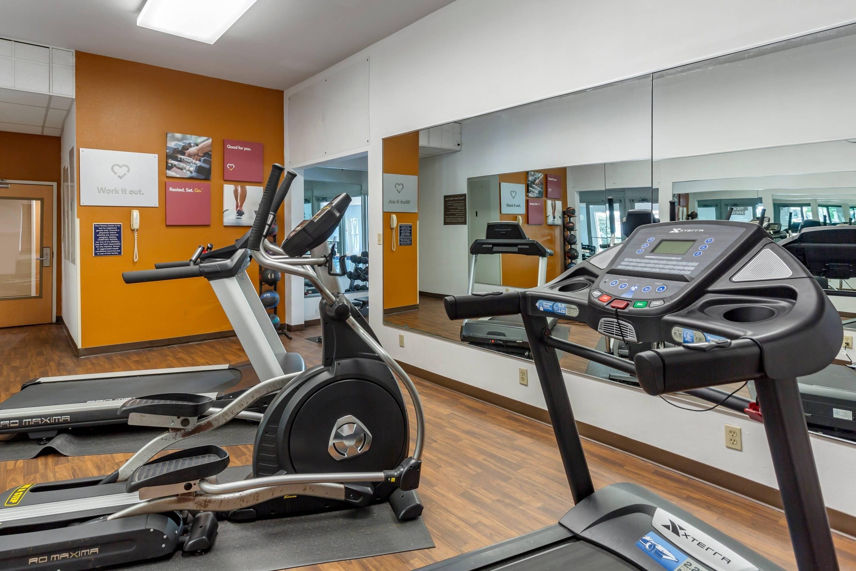 A gym with cardio equipment, including treadmills and stationary bikes, and mirrors on the walls.