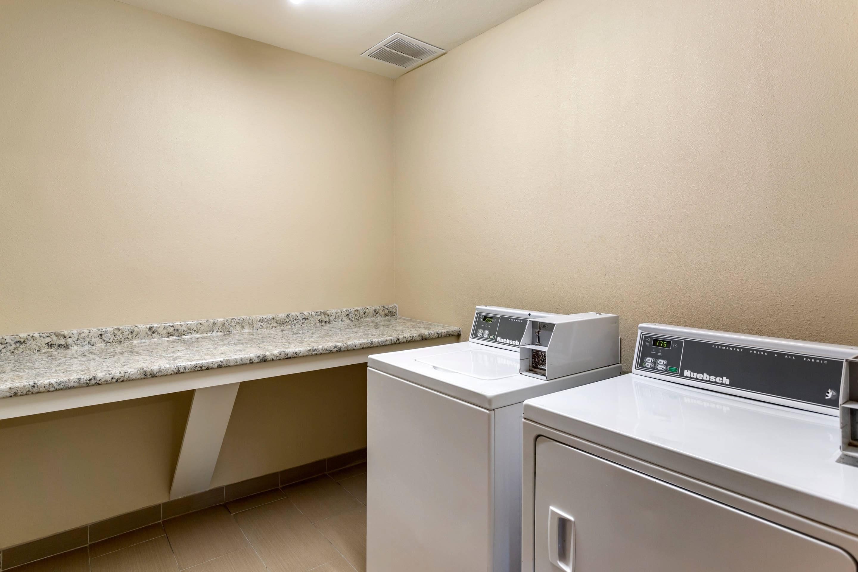 A laundry room with a washing machine, dryer, and a countertop.