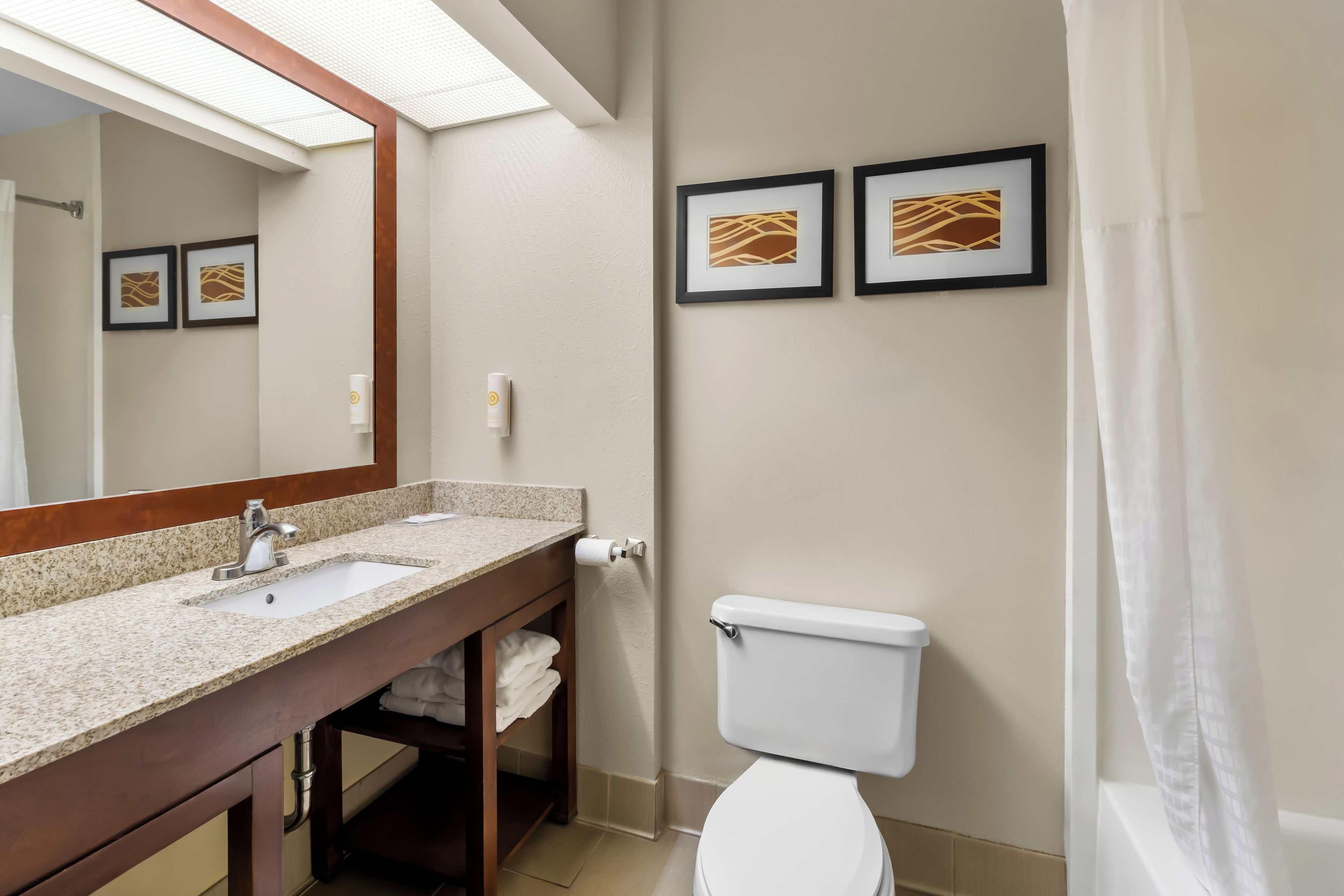 Ein Badezimmer mit Waschbecken, Toilette und zwei gerahmten Bildern an der Wand.