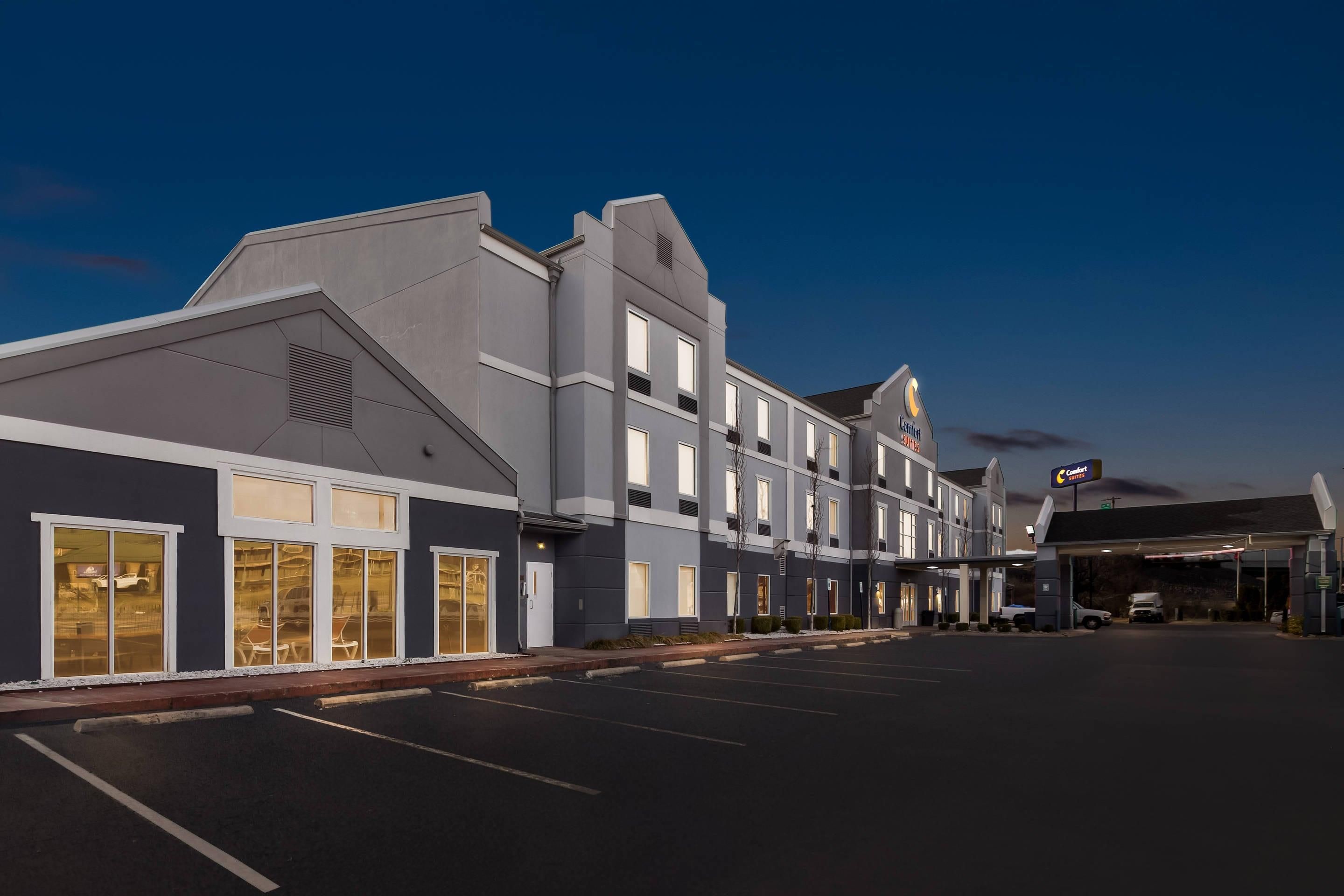 A multi-story hotel with a modern architectural design, featuring large windows and a parking lot in front.