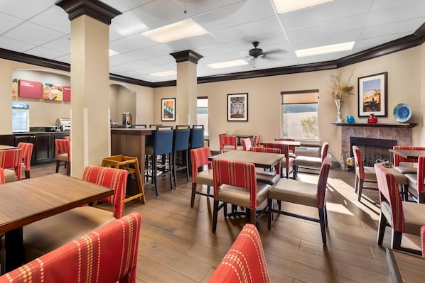 A restaurant with wooden tables and red upholstered chairs, a bar area, and framed pictures on the walls. - Comfort Suites Goodlettsville Rivergate (Goodlettsville)