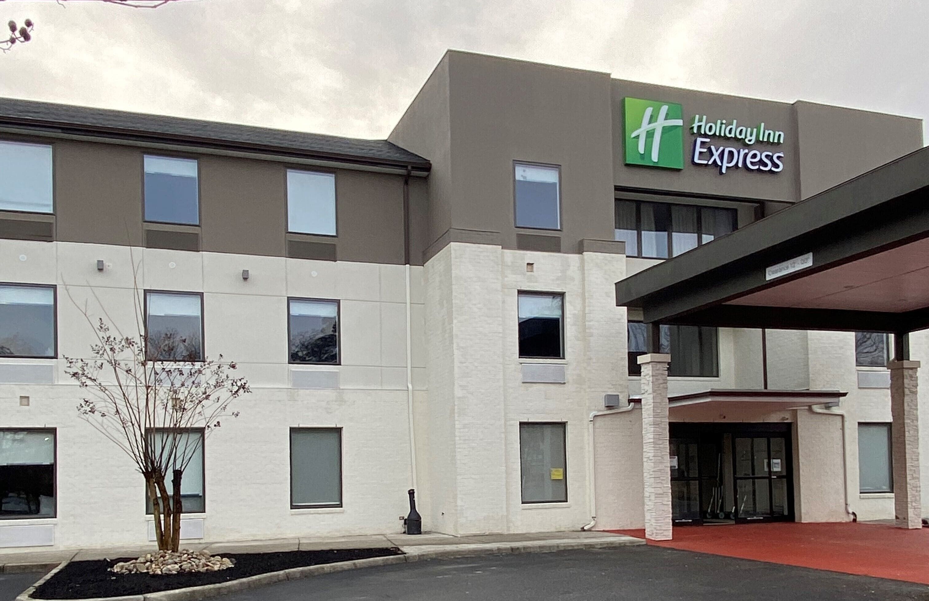 Un bâtiment de la chaîne Holiday Inn Express, doté d’un design moderne, avec un toit plat et un espace d’entrée abrité.