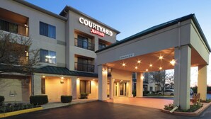 Entrada de un hotel Courtyard Marriott con un área de estacionamiento techada y cielo despejado.