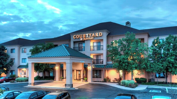 Un hotel Courtyard Marriott con entrada techada, varios pisos y estacionamiento.