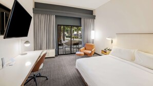 A hotel room with a bed, desk, chair, TV, and a view of the outdoors. - Sonesta Select Phoenix Chandler (Chandler)