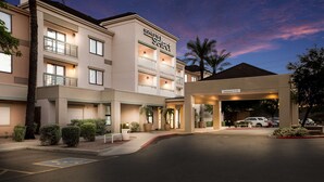 A hotel with a clear entrance, a sign indicating a clearance of 11'-0", and a parking area with a handicapped parking space. - Sonesta Select Phoenix Chandler (Chandler)
