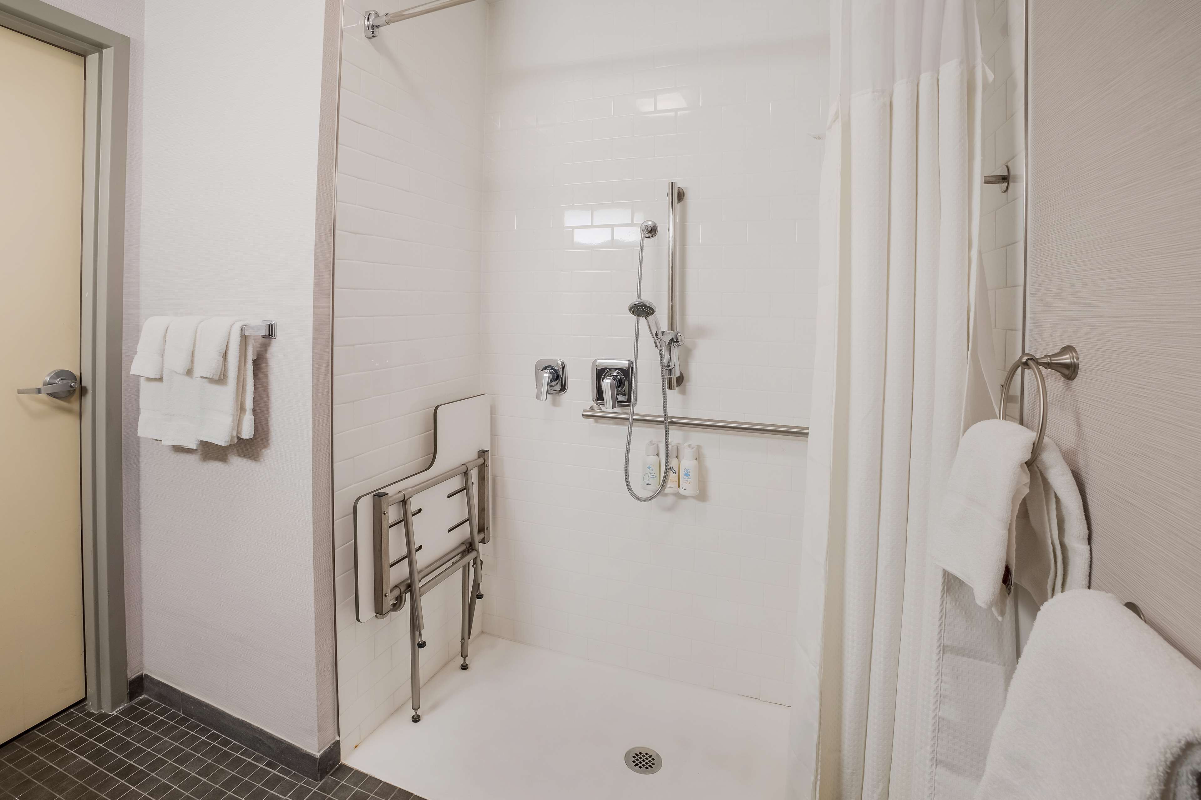 Une douche à l’italienne avec une porte en verre, un porte-serviettes et un pommeau de douche.